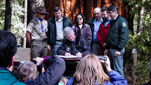 People gathered at Trail of a Hundred Giants, President Bill Clinton signing the Proclamation at a table.